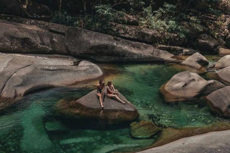 2 girls sitting on a rock in natural pools