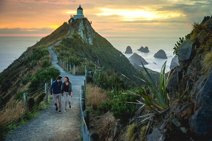 Couple walking away from New Zealand lighthouse