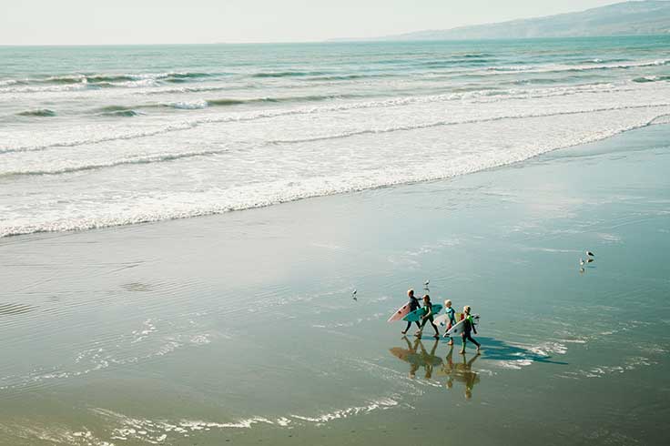 Surfers walking on beach down to water